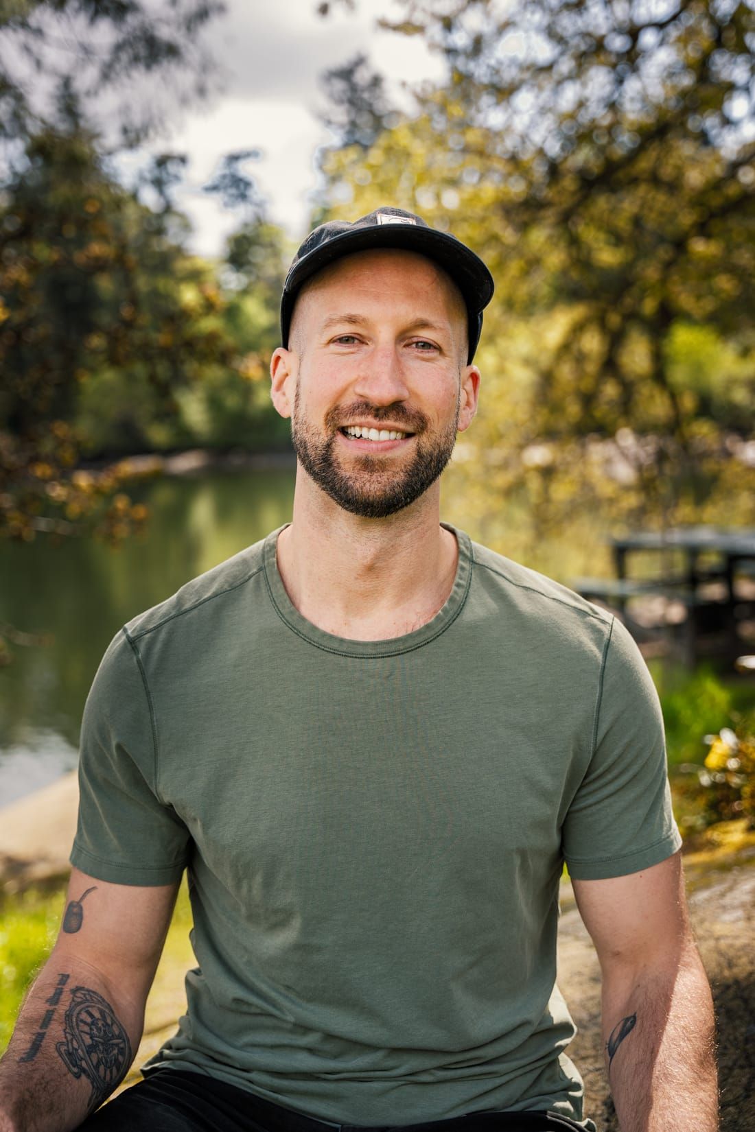 Andras Lenart, Registered Clinical Counsellor, smiling, seated outdoors by a pond in Victoria, BC
